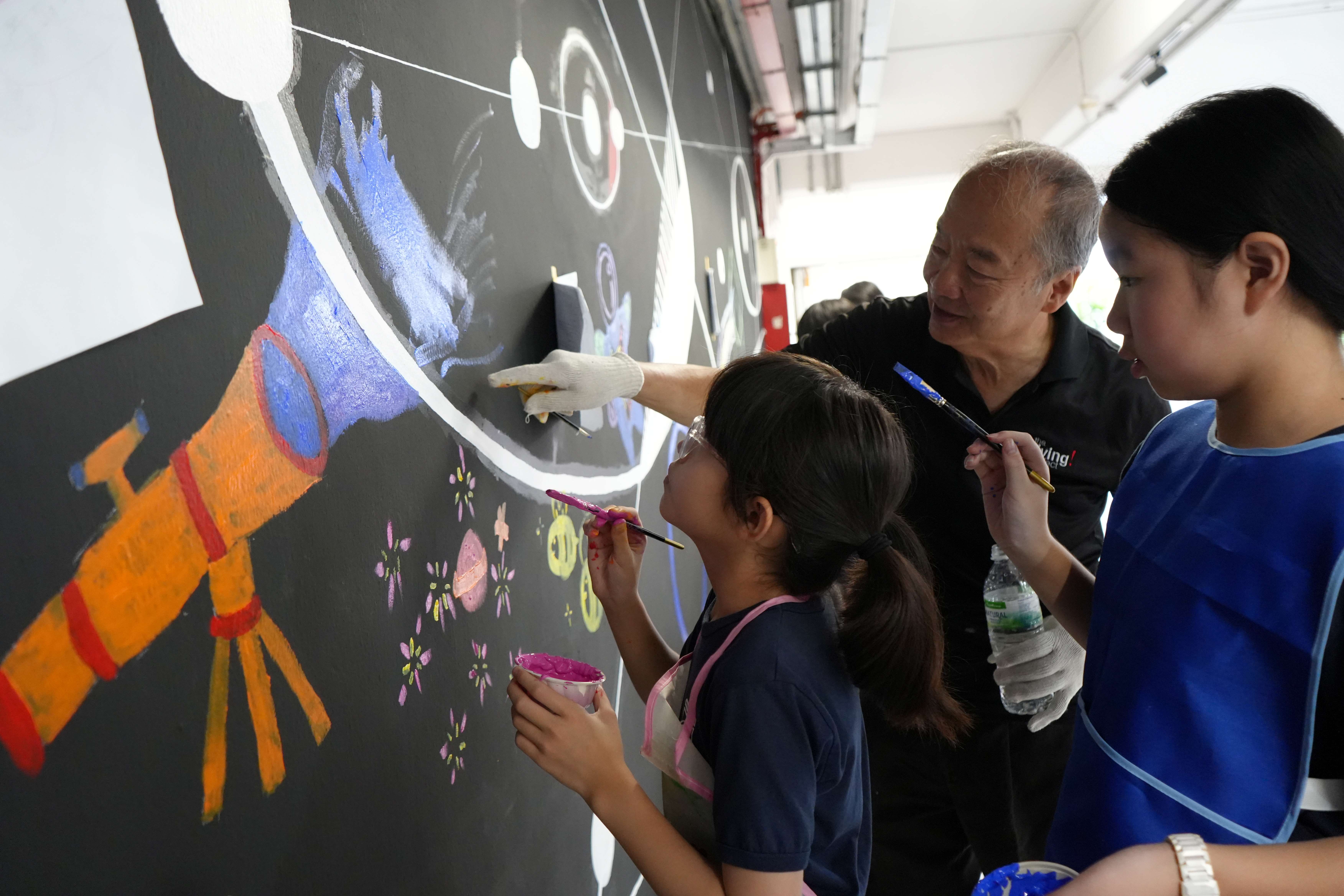 Local artist Mr Sun Yu-li guiding Jieminites to paint on the Art Wall - Quest.